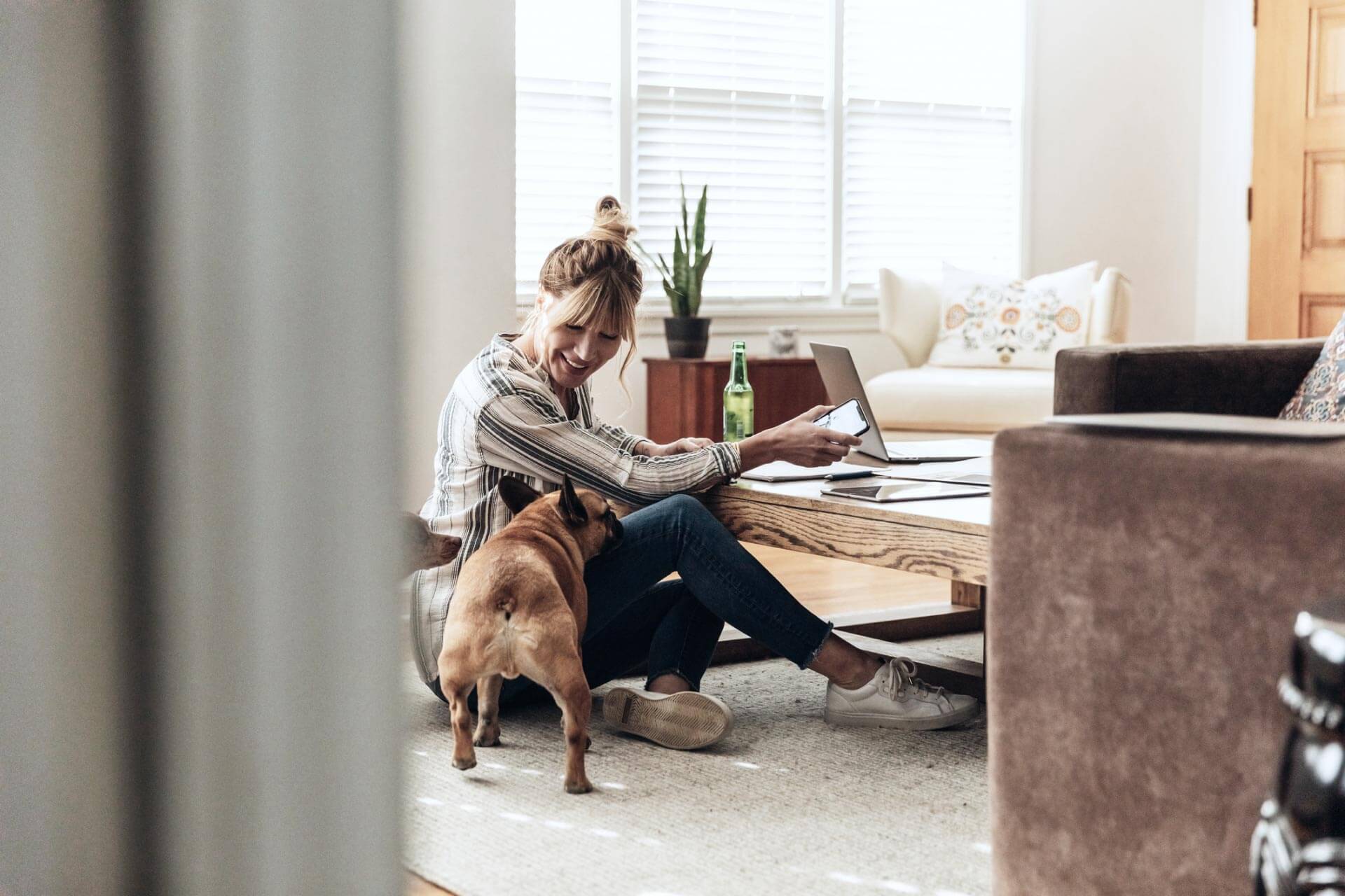 Woman working at home on her laptop with dog next to her.